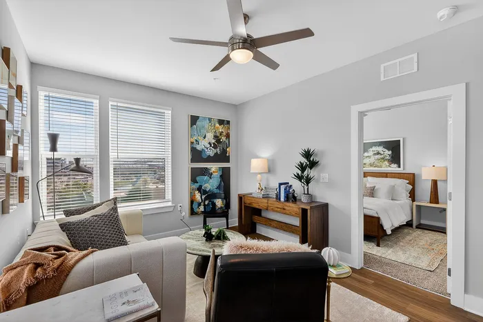 Charming modern living room with stylish decor, cozy sofa, and large windows inviting natural light, adjacent to a beautifully furnished bedroom.