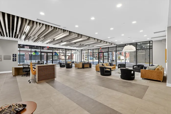 Elegant modern lobby featuring spacious seating area with stylish couches, sophisticated ceiling design, and floor-to-ceiling windows offering abundant natural light.