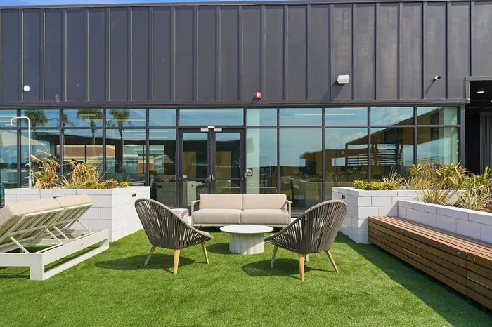 Inviting rooftop terrace with modern outdoor seating, lush green artificial grass, and elegant landscaping, perfect for relaxation and social gatherings.