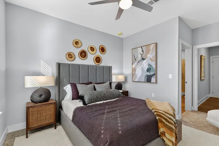 Inviting bedroom with elegant gray accents, plush bedding, modern art, and unique wooden wall decor.