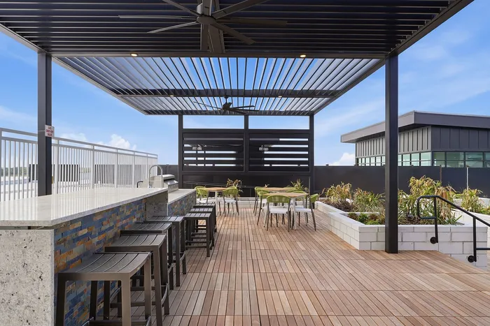 Elegant rooftop patio with modern pergola, cozy seating areas, and lush planters, perfect for outdoor relaxation.