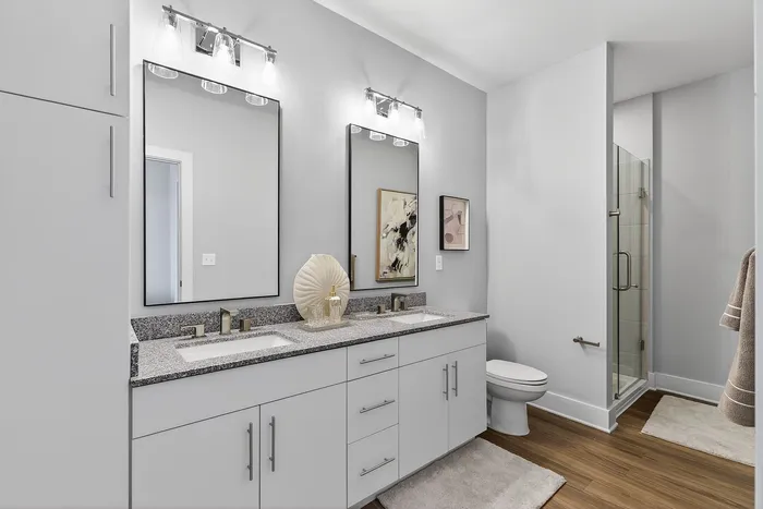 Modern bathroom featuring a double vanity with sleek mirrors, contemporary lighting, and a glass-enclosed shower for a luxurious feel.