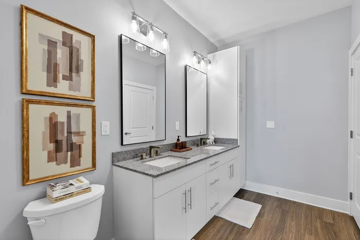 Elegant bathroom with double sink vanity, modern mirrors, and stylish wall art creating a serene ambiance.