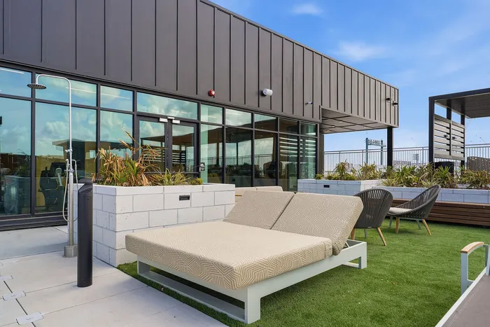 Chic rooftop terrace with modern sun loungers, lush greenery, and elegant outdoor seating, ideal for relaxation.