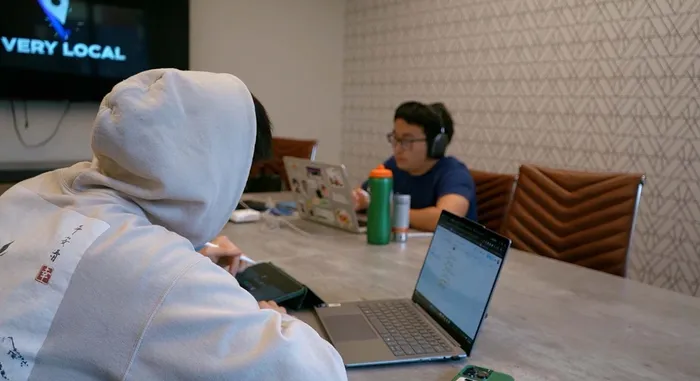 Modern workspace with two people focused on laptops, featuring a cozy atmosphere and sleek design elements.