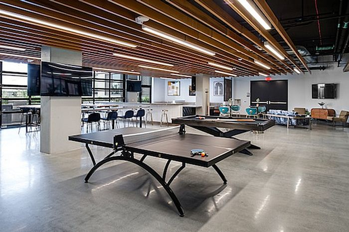 Vibrant recreational area featuring sleek ping pong tables, modern seating, and a stylish ceiling design.