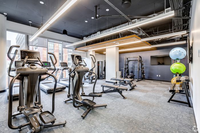 Modern gym facility with state-of-the-art exercise equipment, bright natural lighting, and sleek design.