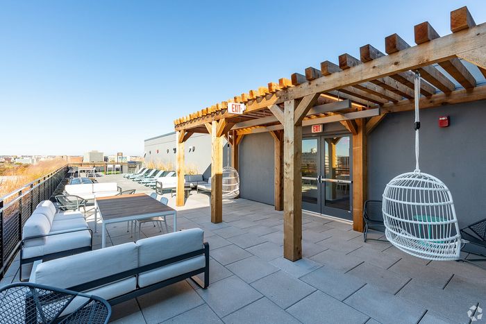 Chic rooftop terrace with stylish seating, wooden pergola, and city views, offering a perfect relaxation spot.