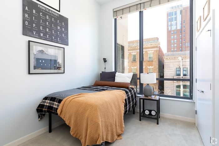 Cozy bedroom with modern decor, featuring a comfortable bed beside a large window with a captivating city view, ideal for urban living.