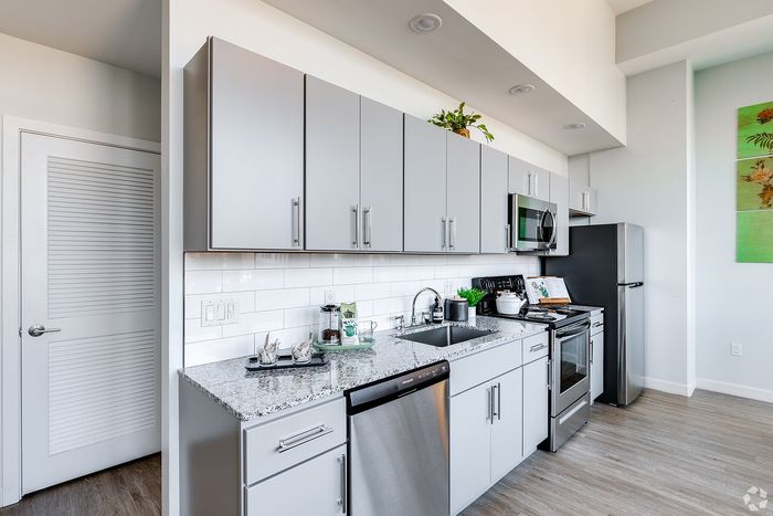 Modern kitchen with sleek gray cabinets, granite countertops, stainless steel appliances, and a stylish backsplash.