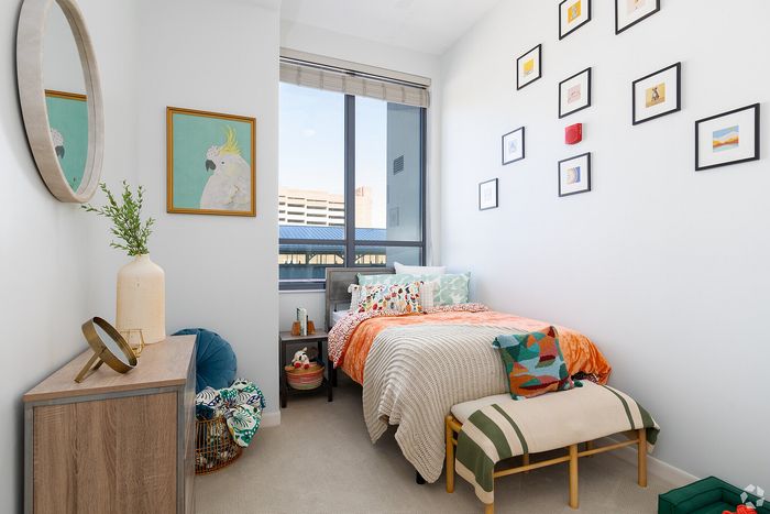 Bright bedroom featuring vibrant decor, large window with city view, and eclectic art display.