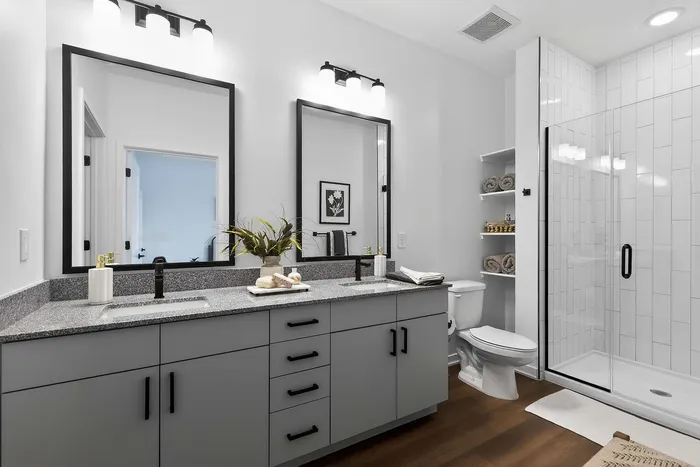 Modern bathroom featuring sleek double vanity, elegant mirrors, and a spacious glass-enclosed shower with stylish tile accents.