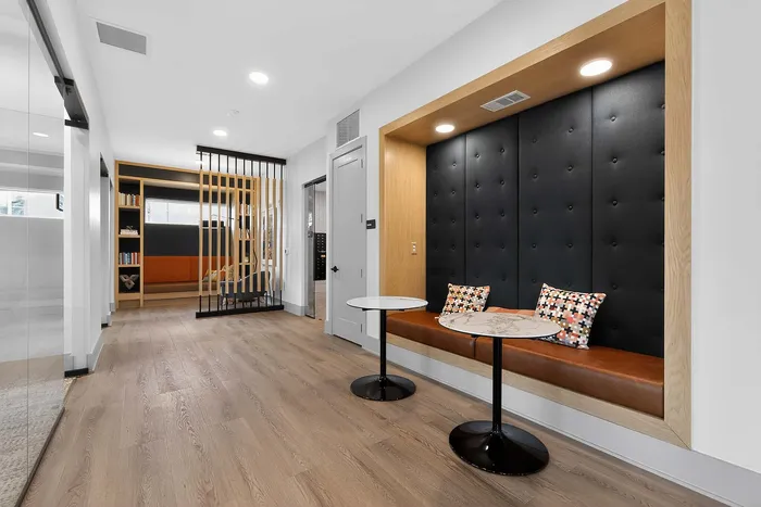 Modern seating nook with leather bench, stylish pillows, and sleek marble tables in a chic apartment hallway.