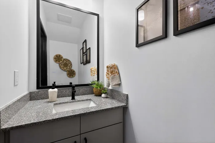 Elegant bathroom boasting a sleek granite countertop, modern fixtures, and artistic wall decor creating a contemporary ambiance.