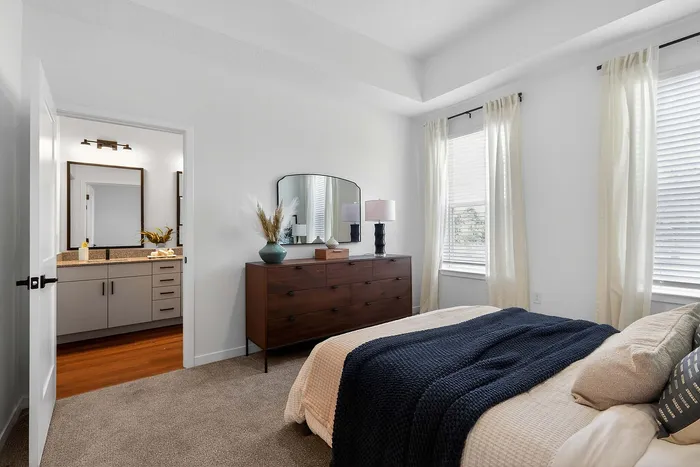 Cozy bedroom featuring a stylish wooden dresser, contemporary decor, and inviting natural light.