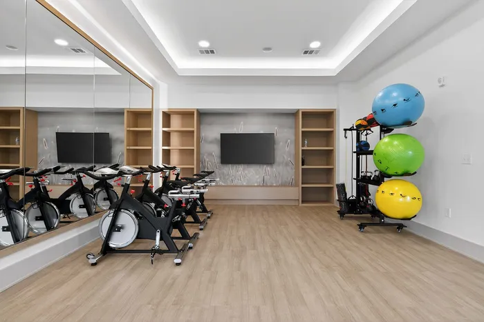 Modern fitness room featuring sleek stationary bikes, mirrored wall, and vibrant exercise balls for a dynamic workout experience.
