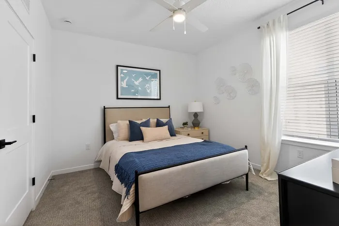 Bright and modern bedroom with plush neutral bedding, bold blue accents, and elegant wall art, perfect for relaxation.