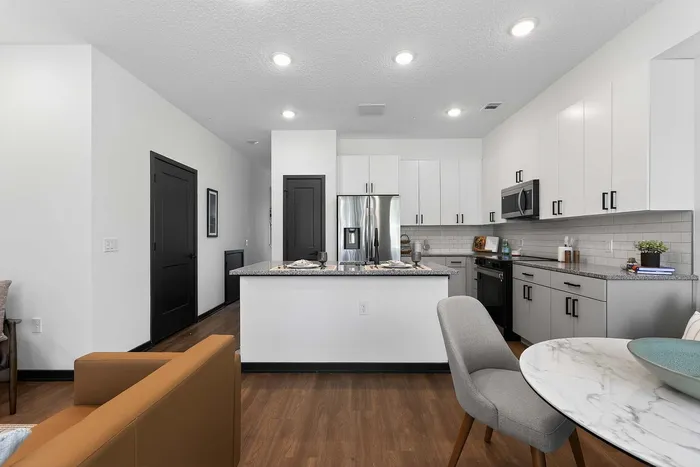 Modern apartment kitchen with sleek white cabinetry, stainless steel appliances, and an inviting bar counter with seating.