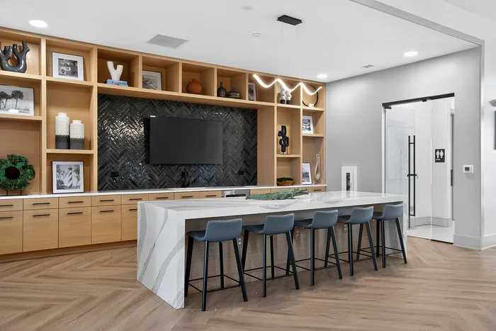 Modern and inviting communal area with elegant herringbone tile accent wall, stylish open shelving, and a sleek marble island with ample seating.