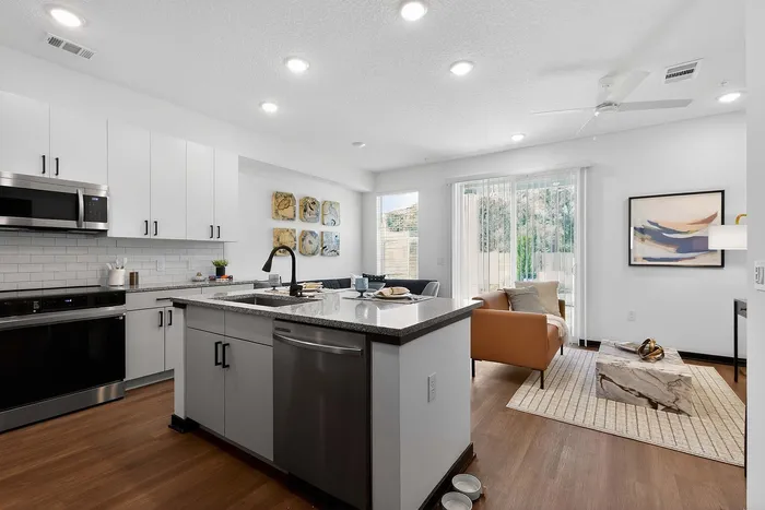 Bright and modern open-concept kitchen with sleek cabinetry, spacious island, and cozy living area featuring a stylish art display and natural light.