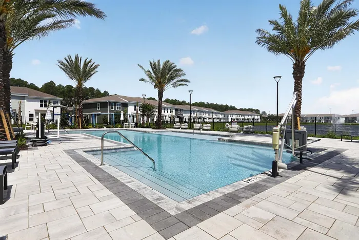 Chic apartment complex featuring a pristine swimming pool surrounded by palm trees and stylish loungers, perfect for relaxation and leisure.