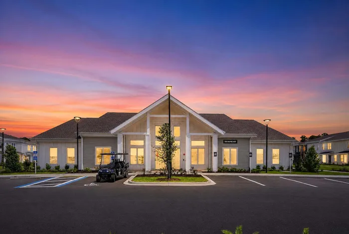 Charming residential building with warm, inviting lighting at dusk, showcasing modern architecture and serene surroundings.