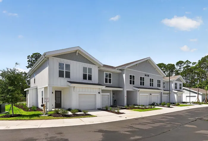 Charming suburban townhouse community with modern architecture, surrounded by lush greenery and blue skies, ideal for family living.