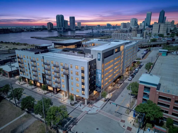 Modern city apartment building with stunning waterfront and skyline views at dusk.
