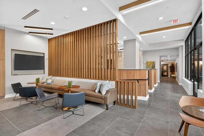 Contemporary apartment lobby with sleek seating area, stylish partition wall, and modern decor.