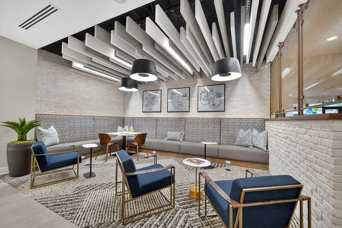 Chic lounge area with stylish decor, featuring accent chairs, modern lighting, and abstract wall art in a cozy setting.