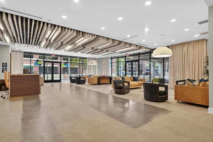 Modern lobby with elegant seating, stylish ceiling design, and floor-to-ceiling windows filling the space with natural light.