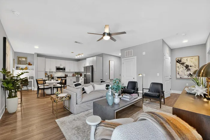 Contemporary open-plan living area with sleek kitchen, cozy dining setup, and stylish decor in a modern apartment.
