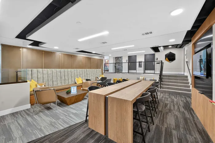 Modern communal lounge with stylish wooden tables, cozy seating area, and sleek d&eacute;cor, perfect for social gatherings.