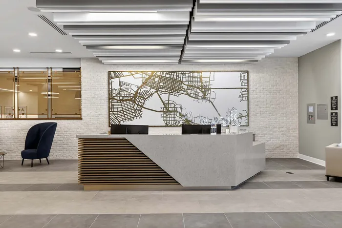 Elegant apartment lobby featuring a modern reception desk, stylish seating, and an artistic map on a brick accent wall.
