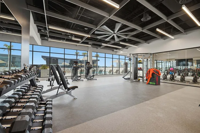 Modern fitness center with sleek equipment, expansive windows, and poolside views, providing a vibrant workout environment.