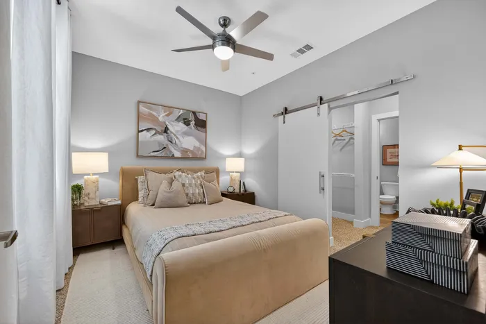 Cozy bedroom featuring a plush bed, elegant decor, and a modern barn door to the ensuite bathroom.
