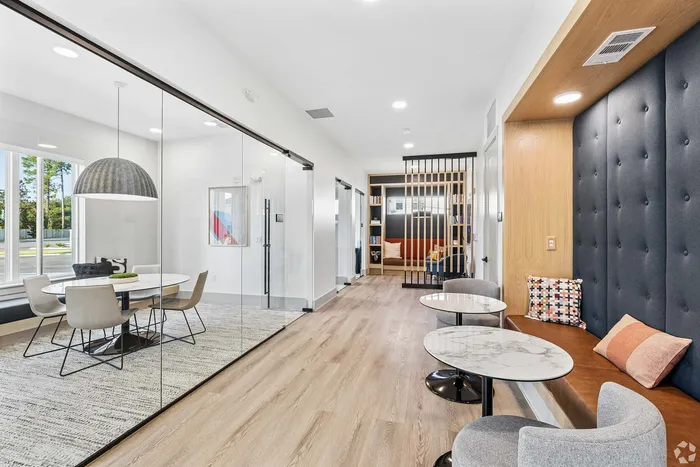 Elegant modern lounge with cozy seating, glass-enclosed dining area, and stylish decor, perfect for relaxation and social gatherings.