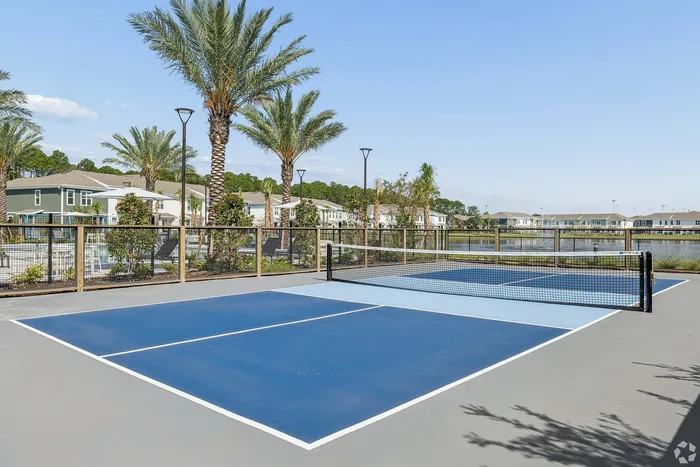 Charming residential community with modern tennis court surrounded by palm trees and serene water views.