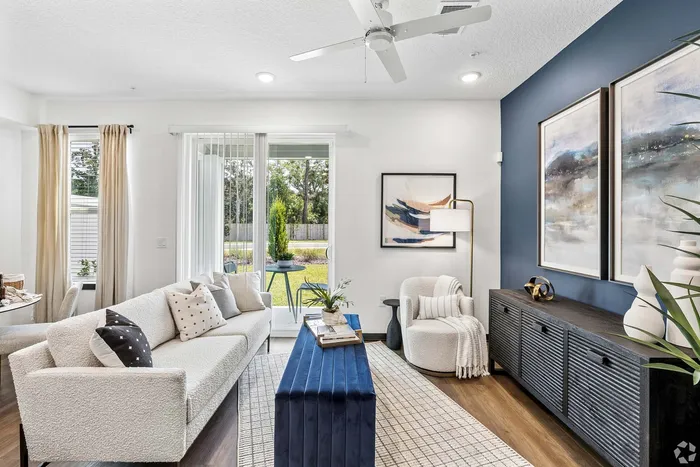 Bright and modern living room with elegant decor, featuring a cozy sofa, chic armchair, and large windows offering a stunning garden view.