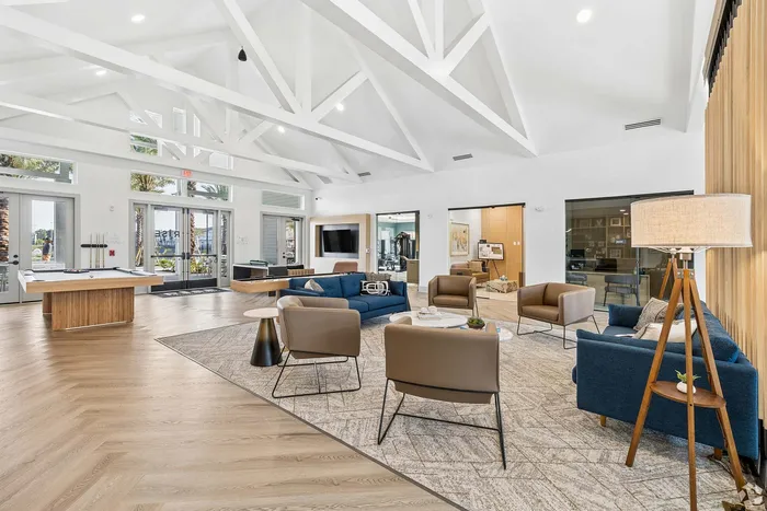 Elegant communal lounge with modern decor, plush seating, and a pool table under vaulted ceilings.