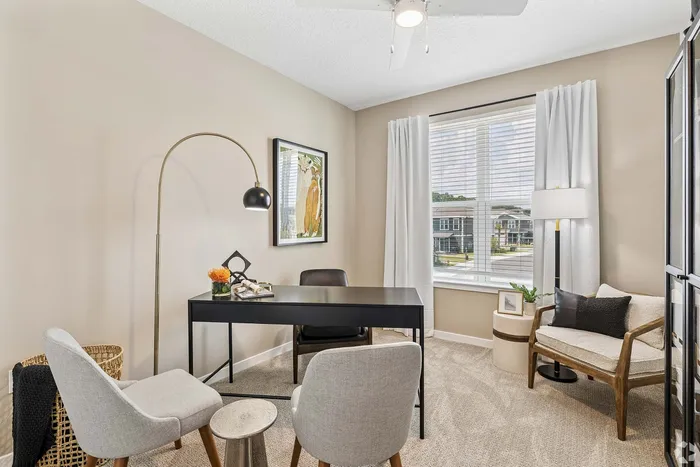 Chic home office with elegant decor, featuring a sleek black desk, stylish seating, and a large window providing ample natural light.