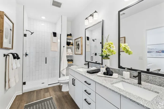 Elegant modern bathroom featuring a spacious glass shower, dual vanity with sleek fixtures, and stylish decor.