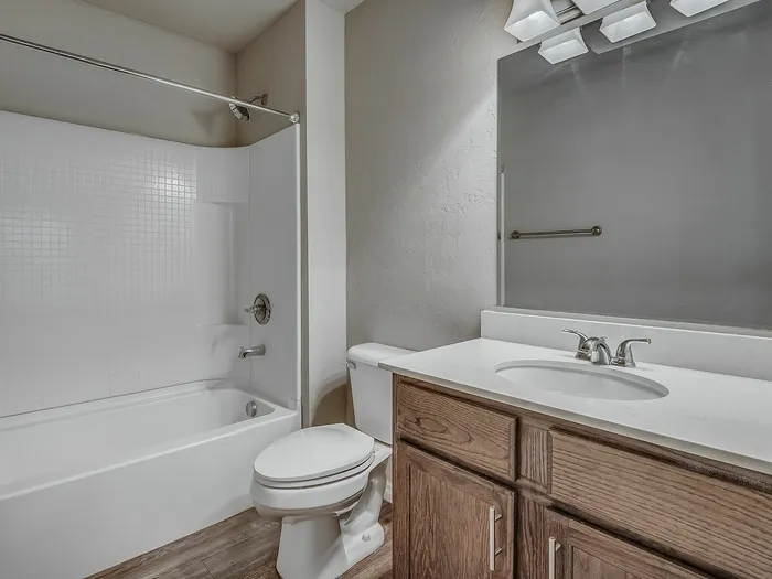 Tasteful bathroom featuring a sleek white tub, modern fixtures, spacious countertop, and wooden cabinetry.