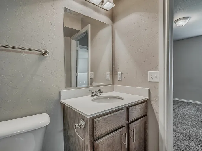Chic bathroom featuring modern fixtures, a sleek vanity, and textured walls leading into a cozy room.