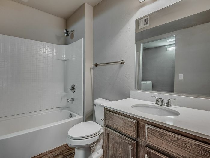 Chic bathroom featuring a modern bathtub, sleek sink with a large mirror, and stylish wooden cabinetry.
