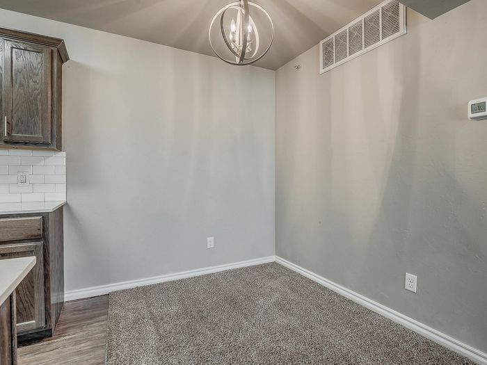 Inviting dining area with plush carpeting, modern light fixture, and wooden cabinetry.