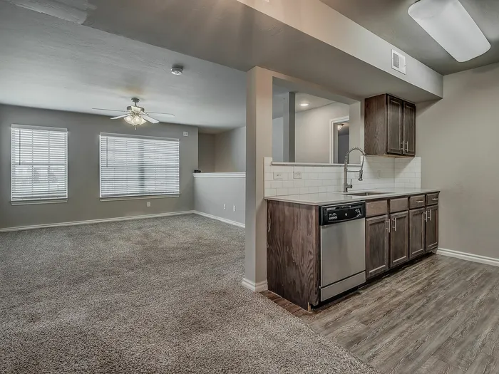 Inviting open-concept living space featuring a cozy carpeted area and modern kitchen with stainless steel appliances.