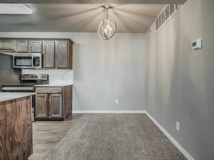Modern kitchen with dark wood cabinetry, stainless steel appliances, and cozy dining space under a stylish pendant light.