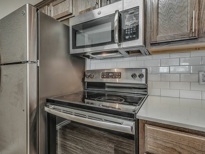 Modern kitchen featuring stainless steel appliances, white subway tile backsplash, and elegant wooden cabinetry.