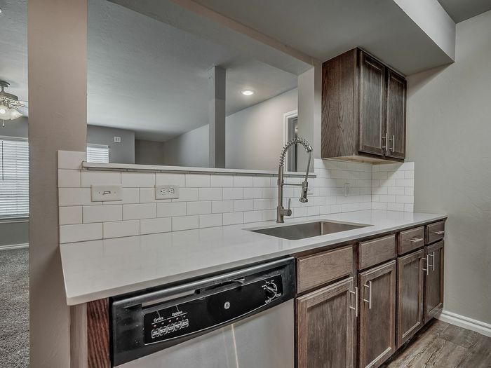 Contemporary kitchen showcasing dark wood cabinets, stainless steel appliances, and a sleek neutral countertop.